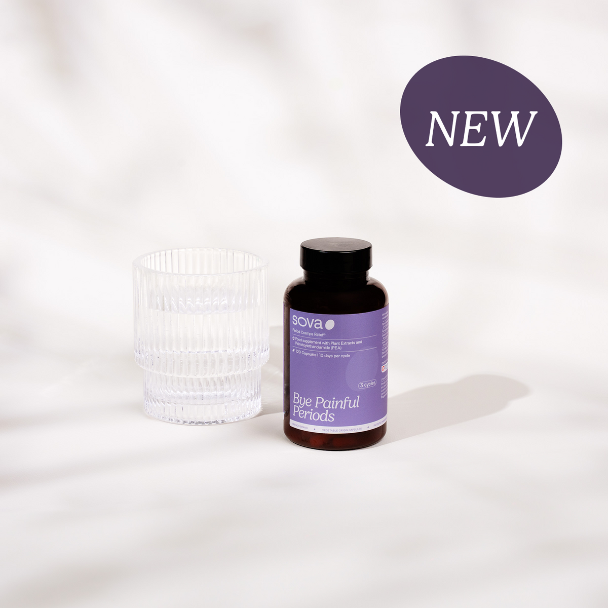 Bye Painful Periods supplement bottle by Sova, displayed next to a ribbed glass on a soft white textured background. NEW label visible.